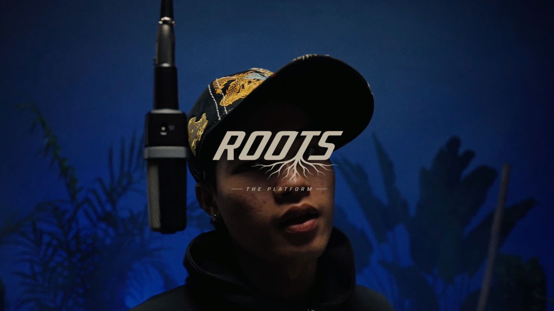 Roots logo lockup over the blue session floor